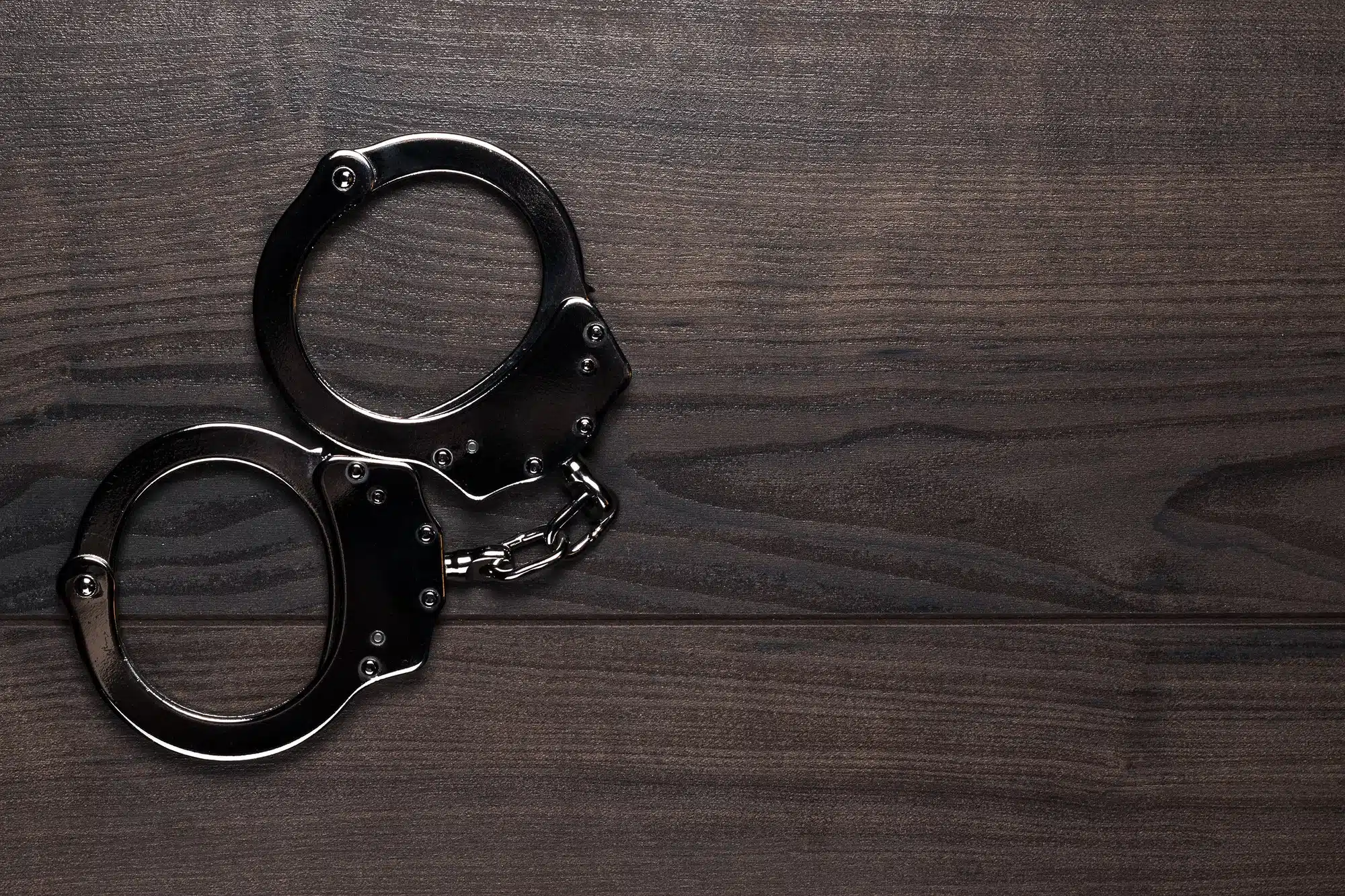 Handcuffs On Brown Wooden Table Background